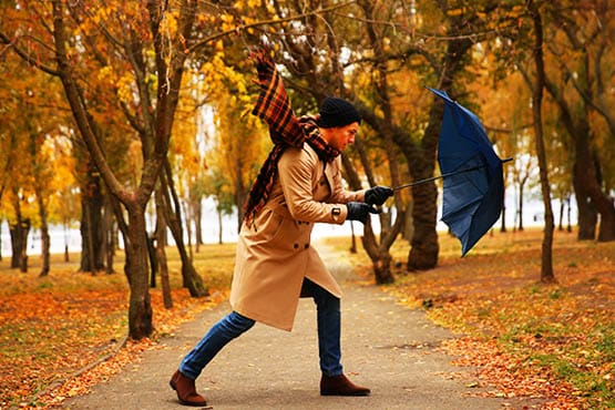 man struggling with umbrella on a windy day