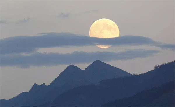 photo of the moon rising over a mountain ridge