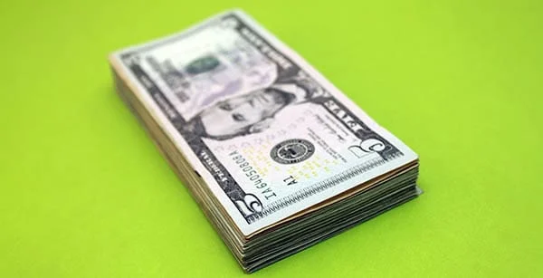 stack of five dollar bills set on a green background