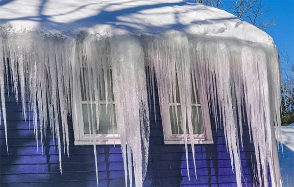 large icicles hanging from a blue house