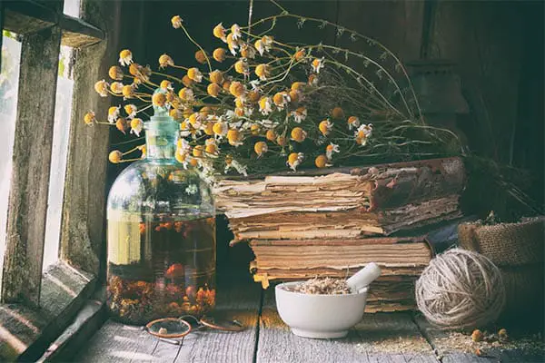 old books, dried flowers, and recipe ingredients in a glass jar